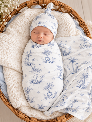 Newborn wrapped in Tiny Yarns cream swaddle with blue safari toile print