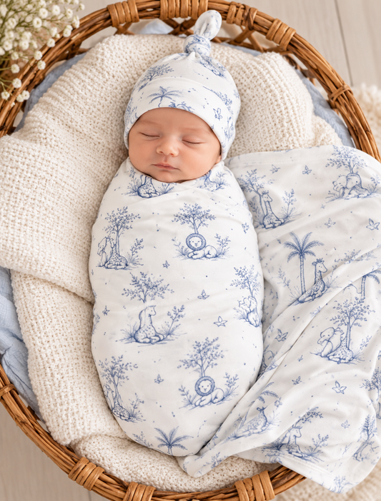 Newborn wrapped in Tiny Yarns cream swaddle with blue safari toile print